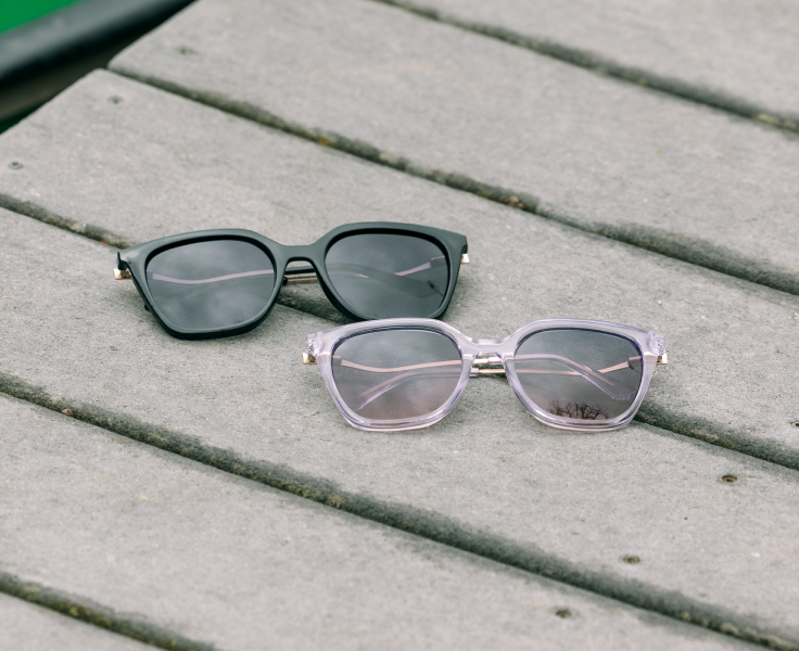 Two pairs of sunglasses on a wooden surface
